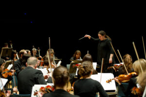 Photographie de la cheffe d'orchestre au milieu des musiciens