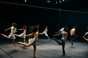 Photographie des danseurs de la pièce exécutant un mouvement chorégraphique aérien