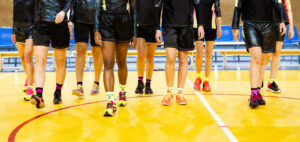 On voit les jambes de plusieurs femmes en basket et tenues de sport. Elles sont dans un gymnase.