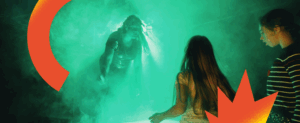Visuel pour le spectacle participatif la Juke-BoxBoum des petits monstres. Dans une épaisse fumée verte, une danseuse mime un monstre et fait face à une petite fille qui danse.