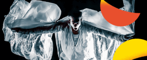 Visuel pour le spectacle de clown de Typhus Bronx. Il s'agit d'une photographie spectaculaire avec des jeux de lumières faisant ressortir sa grande blouse blanche qu'il secoue en bougeant les bras.