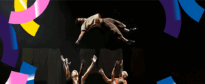 Visuel pour le spectacle de cirque Moya. Quatre circassiens forment une ronde et tendent les bras pour rattraper un acrobate lancé en l'air. Ce-dernier est allongé sur le dos et écarte les bras.