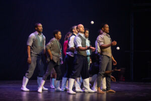 Photo des artistes du spectacle Moya en train de danser le Gumboots en bottes blanches