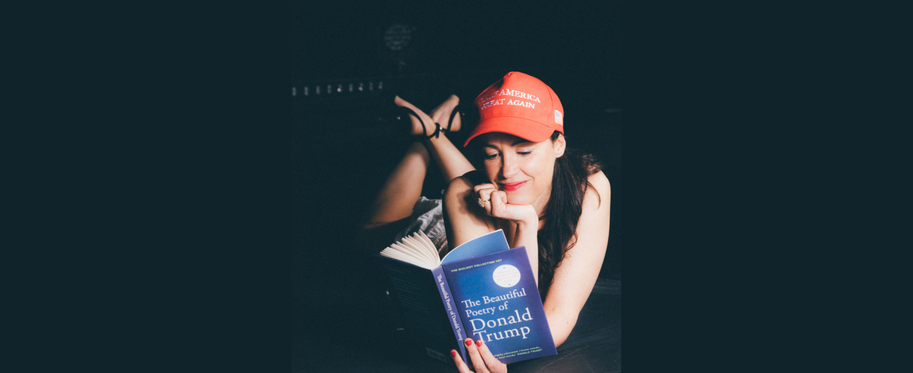 Photo d'Audrey Vernon en train de lire un livre intitulé "The Beautiful Poetry of Donald Trump" et portant une casquette "Make America Great Again".