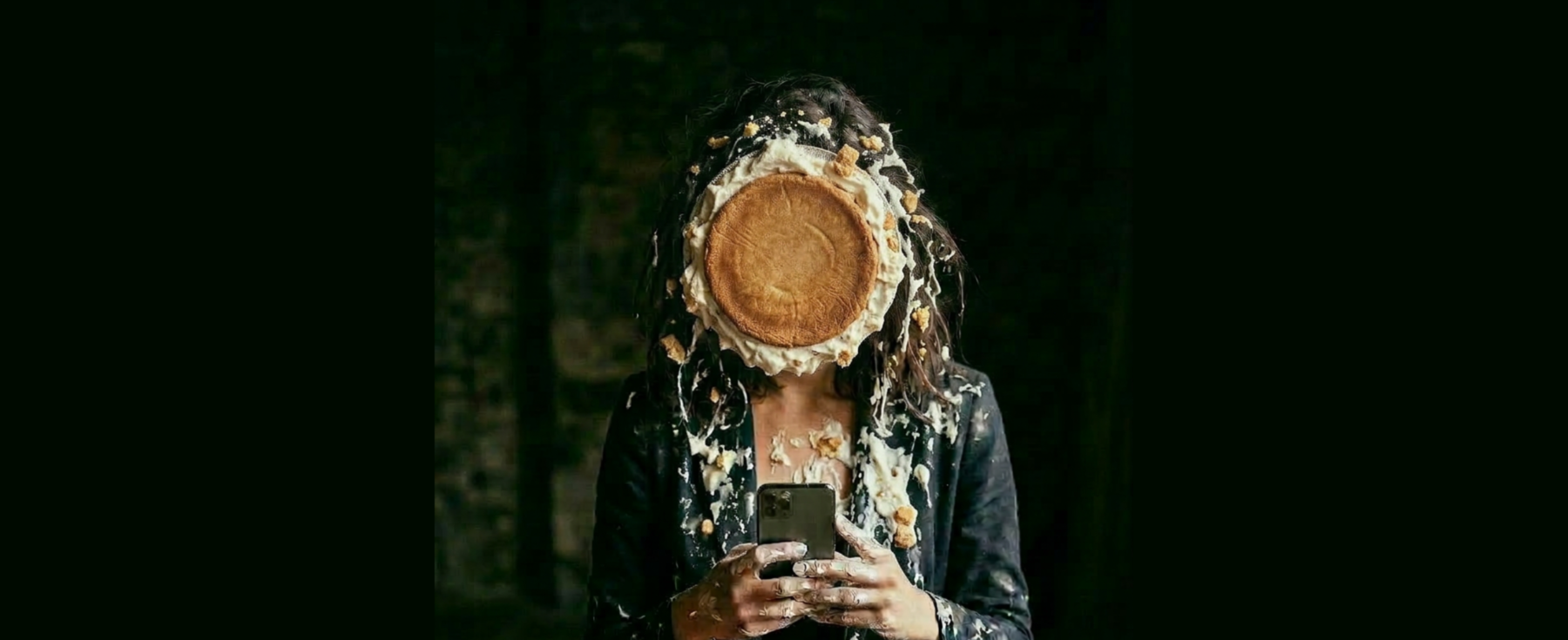 Une femme navigant sur son smartphone et entartée d'un gâteau.